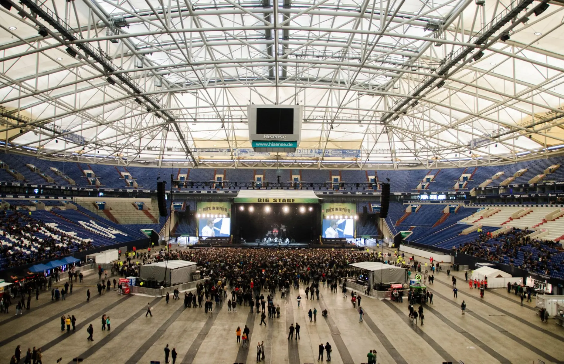 Interior view of Accor Arena in Paris featuring a large stage, crowd, and distinctive white geometric ceiling structure