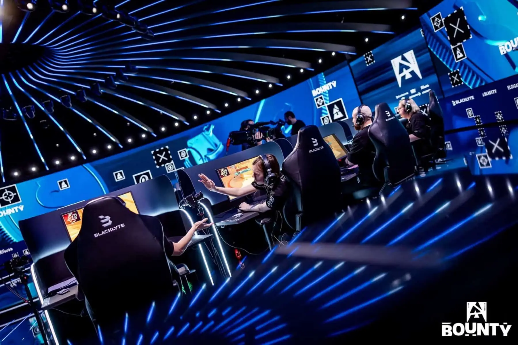 Professional esports players competing at the BLAST Bounty tournament stage with blue neon lighting