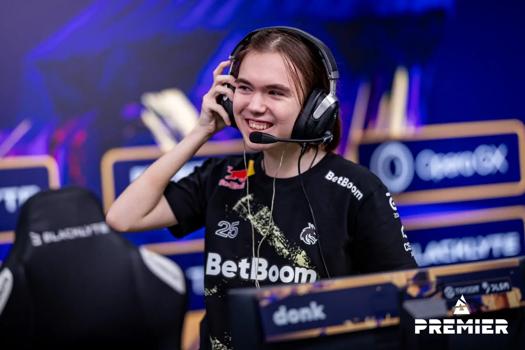 Professional CS2 player donk wearing a Team Spirit jersey and headset while smiling at a tournament.
