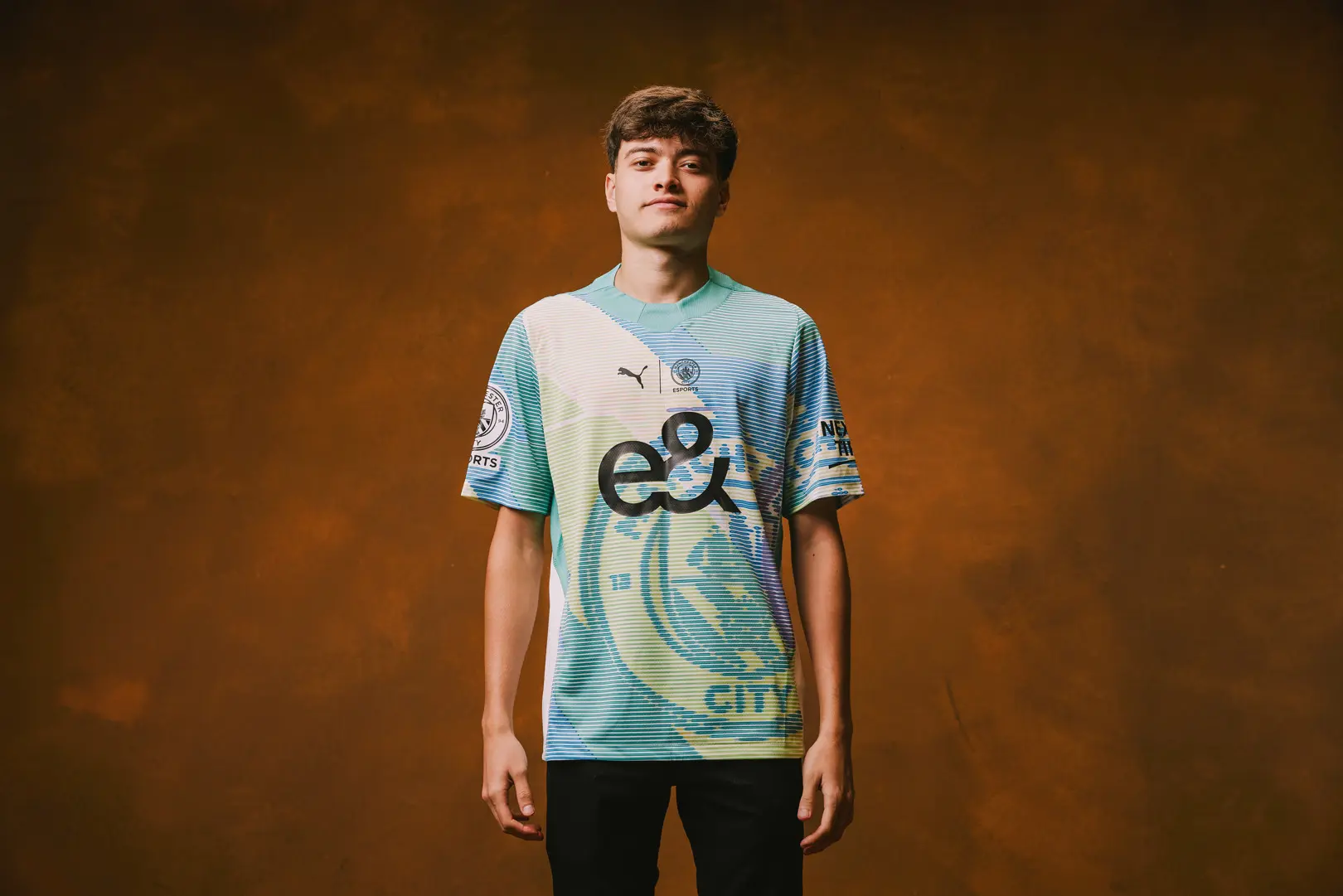 Portrait of Matias Bonanno wearing a light blue Manchester City eSports jersey against a brown background