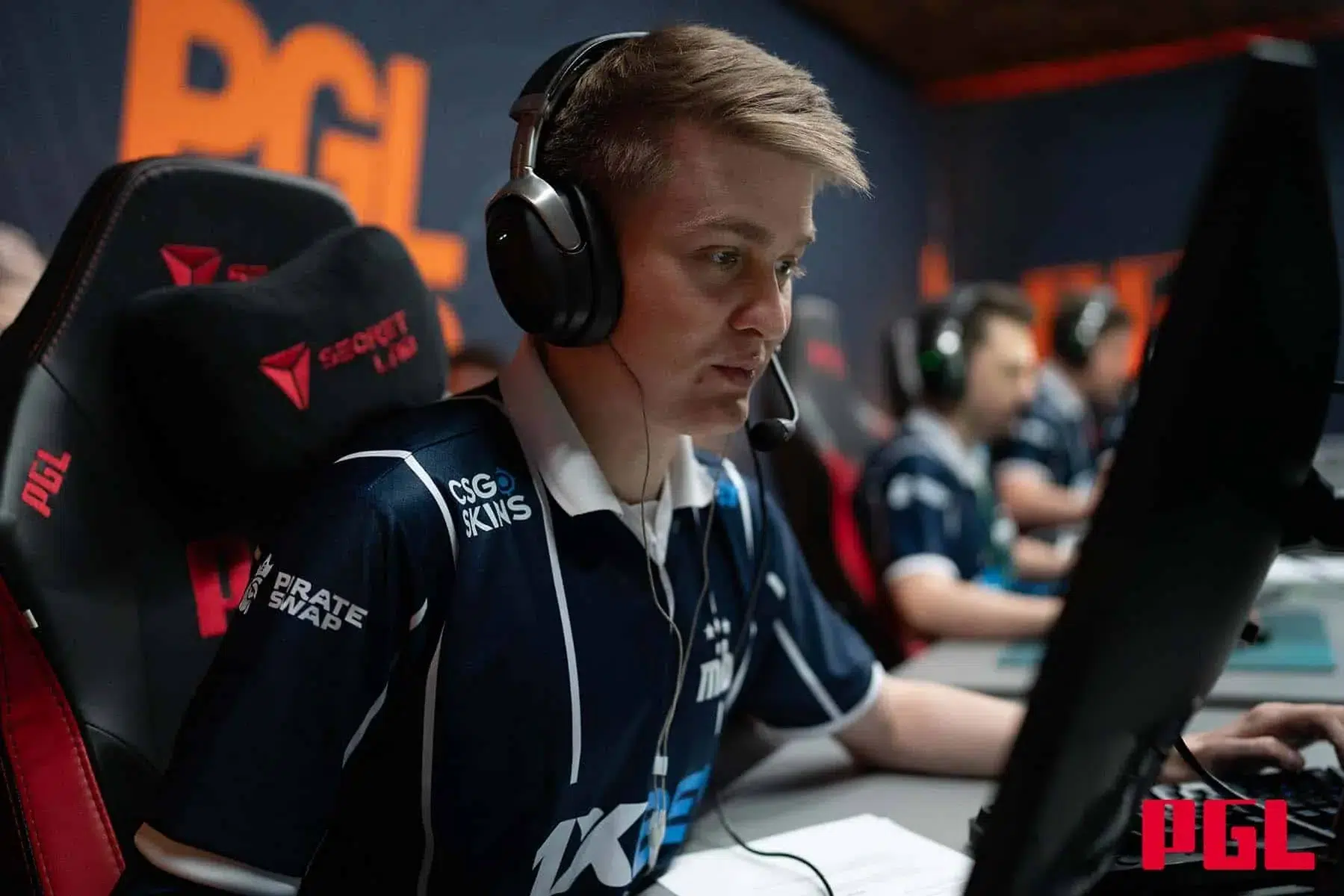 Professional esports player Qikert wearing a team jersey and headset during a PGL tournament match