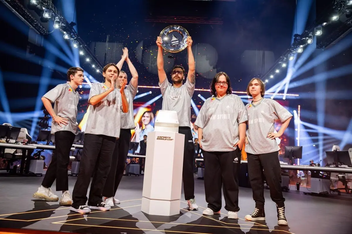 Team Spirit players holding a trophy on the Esports World Cup stage