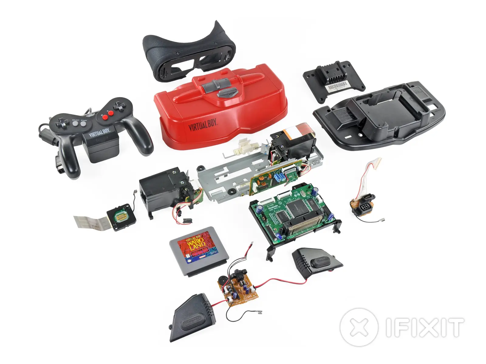 A disassembled Nintendo Virtual Boy console showing the red housing, controller, and internal circuit boards.